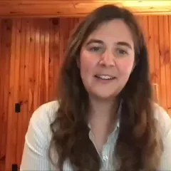 Fish biologist Kate Bemis, a light-skinned woman with long brown hair, sitting in a room with wood paneling behind her.