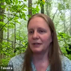 Kristina Anderson-Teixeira, a woman with long brown hair,  in front of small trees with green leaves in a forest.