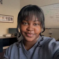 A smiling woman with medium-dark skin tone in a blue sweater