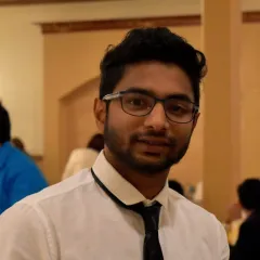 A man with medium-dark skin tone with dark hair and glasses in a white shirt and black tie