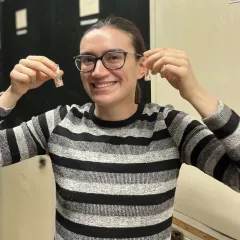 Woman wearing glasses and striped shirt holding vials