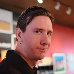 A light-skinned man with dark hair and earrings in his right ear