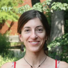 A woman smiling in front of a tree