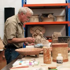 Ron Bishop examining ceramic vessels in a museum lab