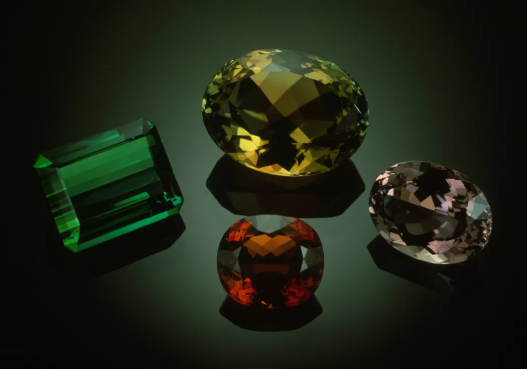 four colorful (green, yellow, red, and pink) gems on black background