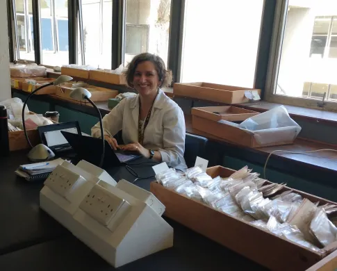 Briana in a sunlit laboratory surrounded by fossils and scientific equipment