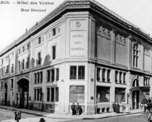 Corner of a four-story stone building with two men standing in front