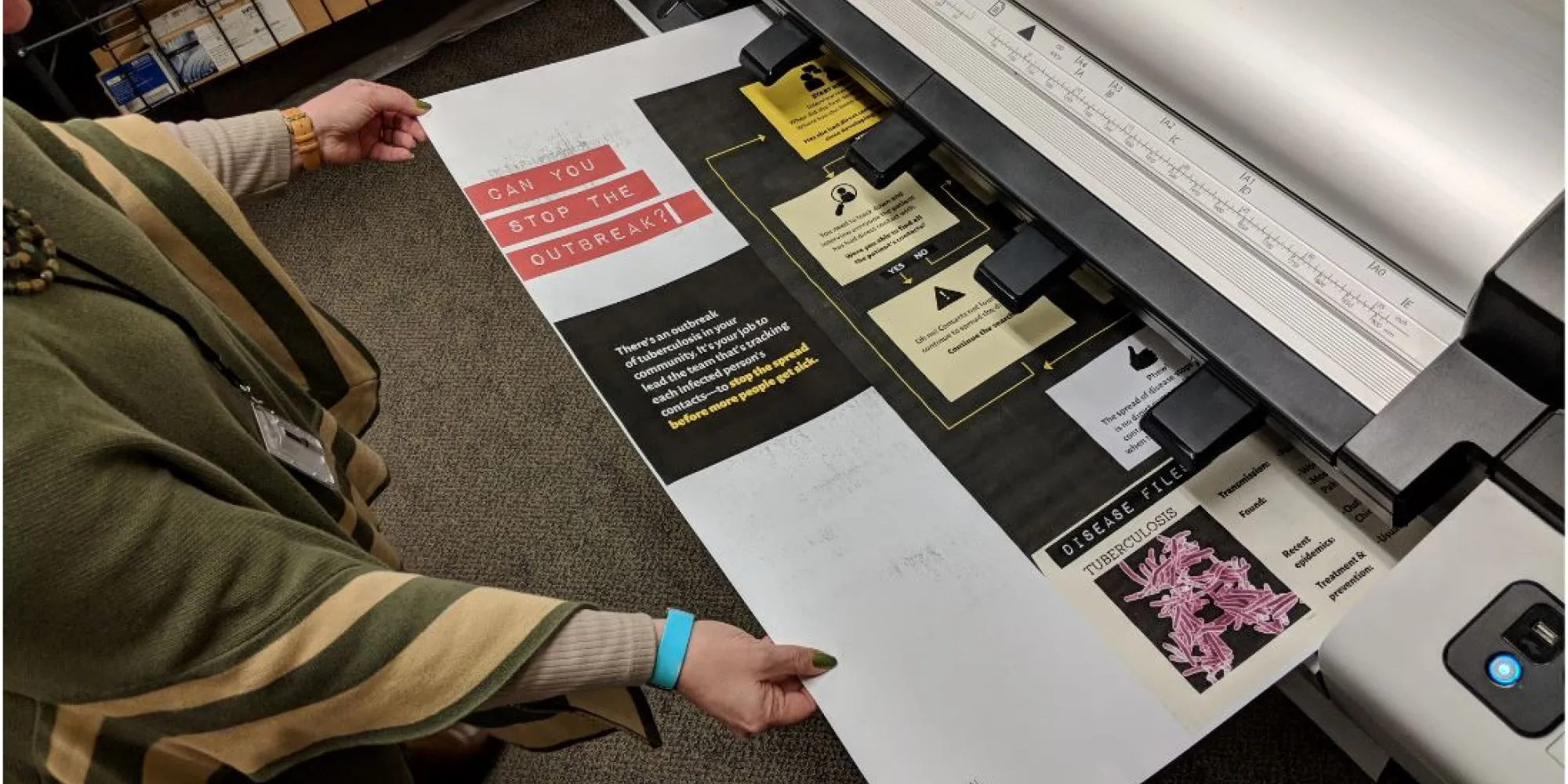 A large poster coming out of a printer being grabbed by two hands