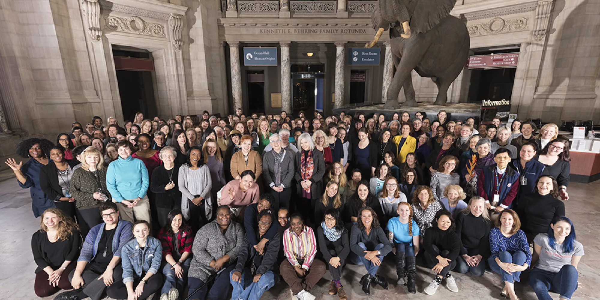 A group photo in the rotunda of museum in front of the elephant with all women who work in the museum