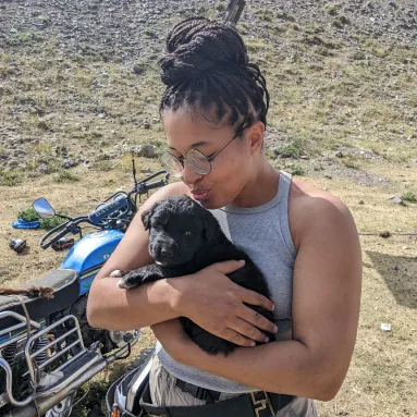 image of women with glasses in a grey tank top holding a dog