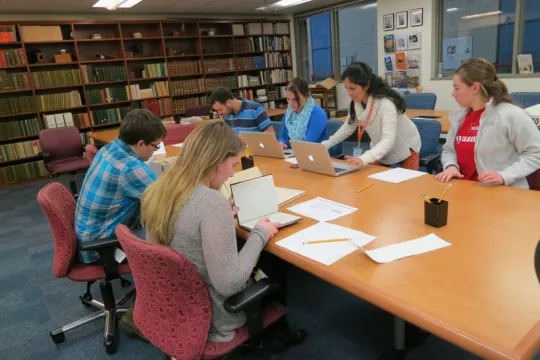 People sitting at a desk looking over archival materials.