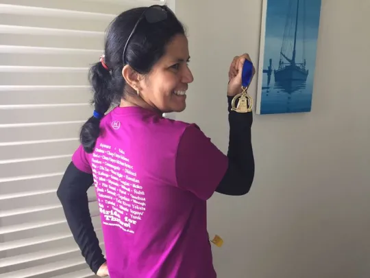  Gabriela Pérez Báez holding a marathon medal wearing a Stride for Thrive shirt.