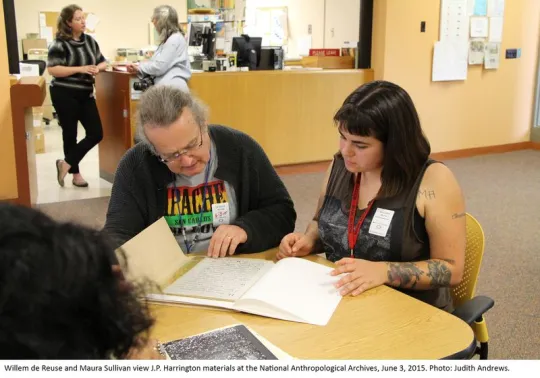 Two people sitting at a desk looking over archival material.