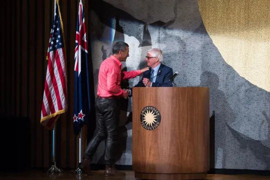 Two men shaking hands on a stage.