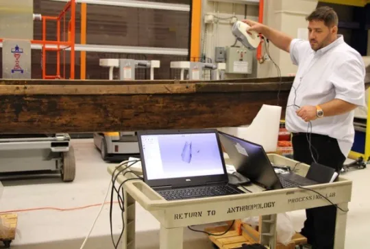 Man using a hand-held 3D scanner to scan the wa'a (canoe)