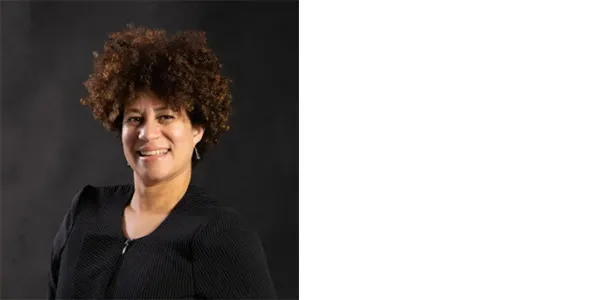 A smiling, medium-skinned woman with brown, natural hair and wearing a black shirt.