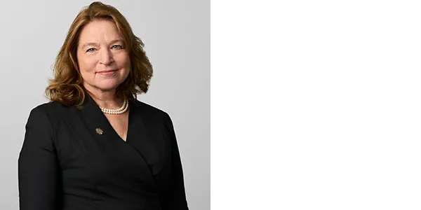 Portrait of Ellen Stofan, a light-skinned woman with shoulder length brown hair, wearing a black top, a pearl necklace, and a Smithsonian sunburst gold pin