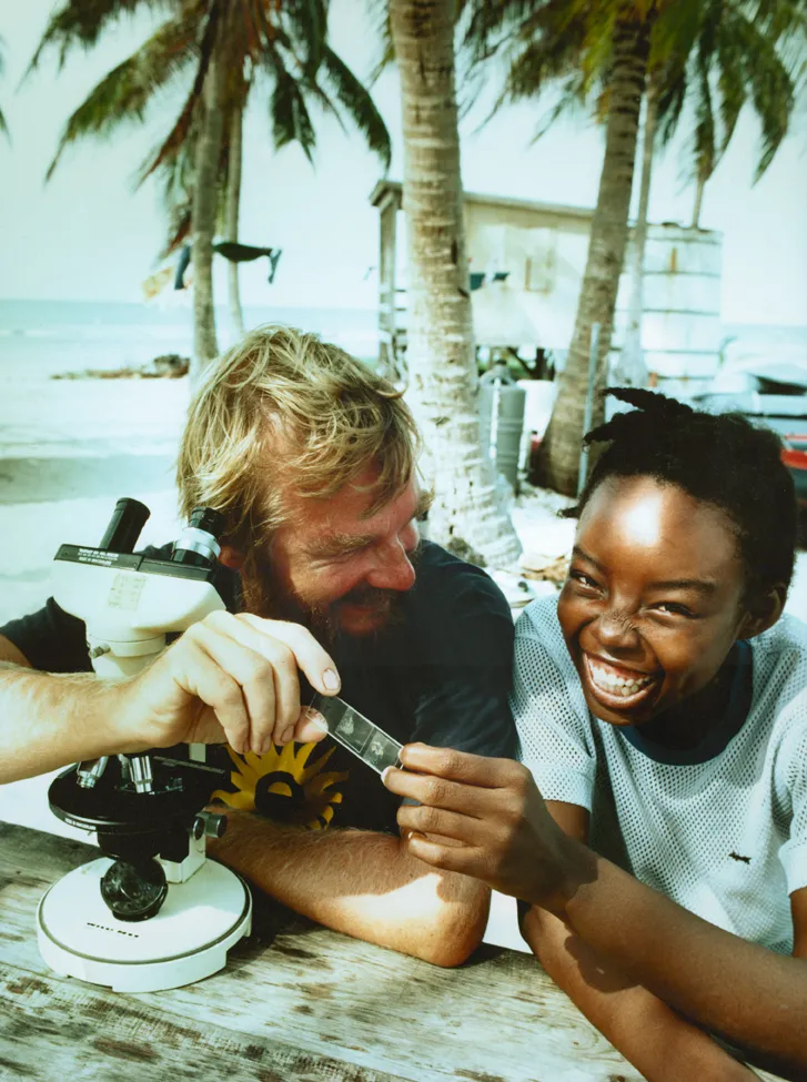 a scientist and a student with a microscope and a glass slide
