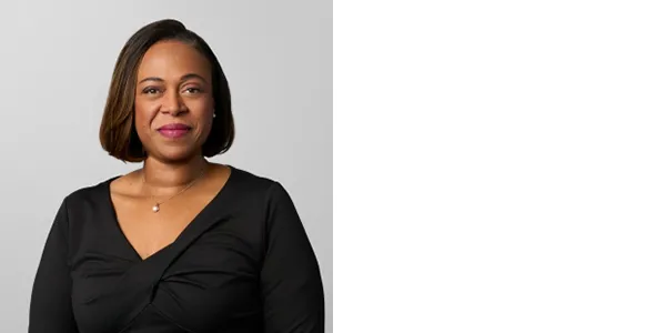 Portrait of Monique Chism, a medium-skinned woman with neck-length brown hair, wearing a black top and a necklace.