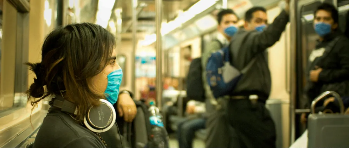 a woman wearing a medical mask sitting on train