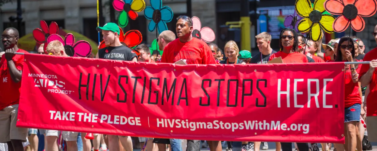 a group of people holding a red banner that reads HIV stimga stops